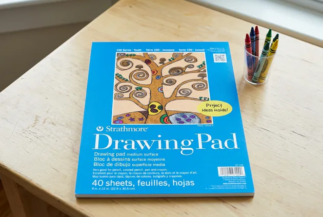 Strathmore 100 Series Youth Drawing Pad on a desk with colored pencils
